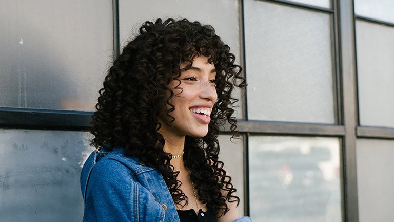 Lachende vrouw met krullend zwart haar 