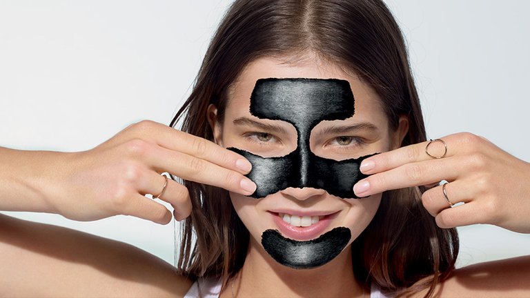 Lachende vrouw met houtskool masker voor de vette huid 